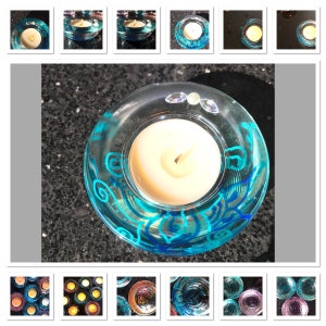 Pode incluir: Porta-velas de vidro azul-esverdeado com um design de espiral azul. Os porta-velas estão cheios de velas de chá brancas.