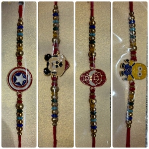 Könnte beinhalten: Vier farbenfrohe Armbänder mit roten Kordeln und dekorativen Anhängern. Eines zeigt ein Captain America-Schild, ein anderes einen Mickey Mouse-Kopf, ein Spider-Man-Emblem und einen Minion-Charakter. Die Armbänder haben goldene, blaue und rote Perlen.