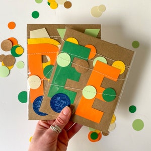 May include: A set of three cards with the letters "E", "E", and "P" cut out of orange and green paper. The letters are decorated with a string of small, colorful circles. The cards are on a brown background and have the text "Always in Stitches" on one of the cards.