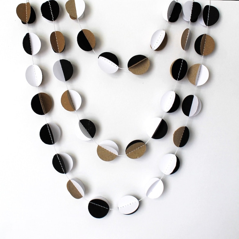 May include: A black, white, and brown paper garland with circles cut in half. The circles are strung together with white thread.