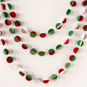 May include: A festive garland made of paper circles in red, green, white, and brown. The circles are layered to create a 3D effect. The garland is strung together with white thread.