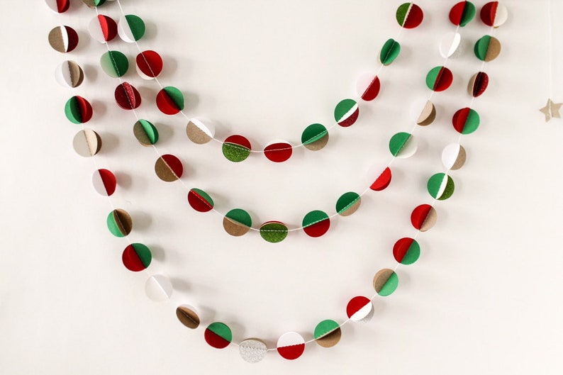 May include: A festive garland made of paper circles in red, green, white, and brown. The circles are layered to create a 3D effect. The garland is strung together with white thread.