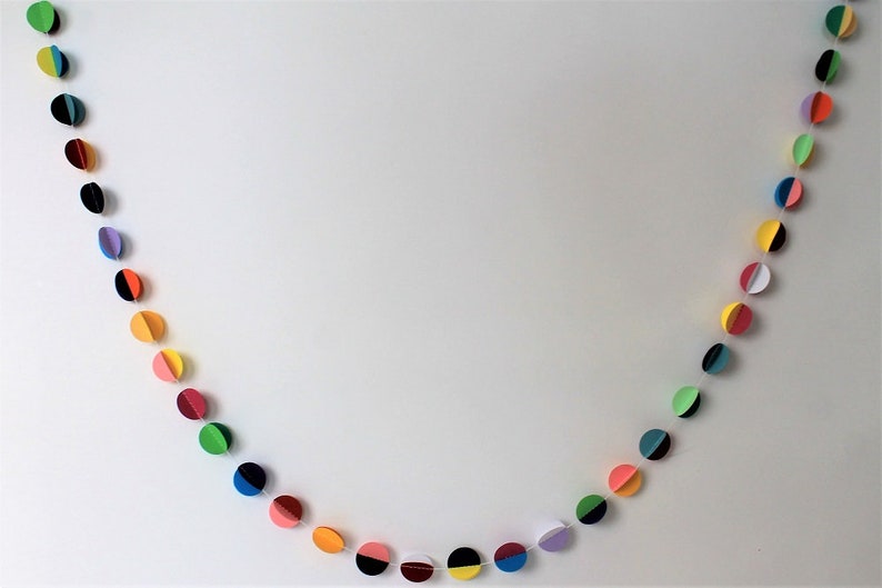 May include: A colorful paper garland with circles in various colors, including green, yellow, pink, blue, and black. Each circle is cut in half and the two halves are joined together to create a three-dimensional effect.