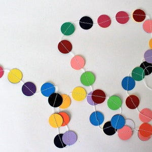 May include: A colorful paper circle garland with alternating colors of red, pink, yellow, green, blue, purple, and black. The garland is strung on white string.