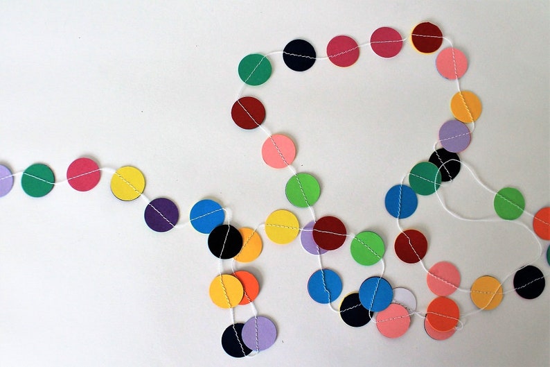 May include: A colorful paper circle garland with alternating colors of red, pink, yellow, green, blue, purple, and black. The garland is strung on white string.
