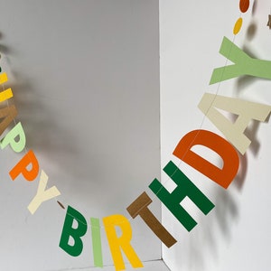 May include: A colorful paper banner with the words "Happy Birthday" in green, yellow, orange, and brown letters.