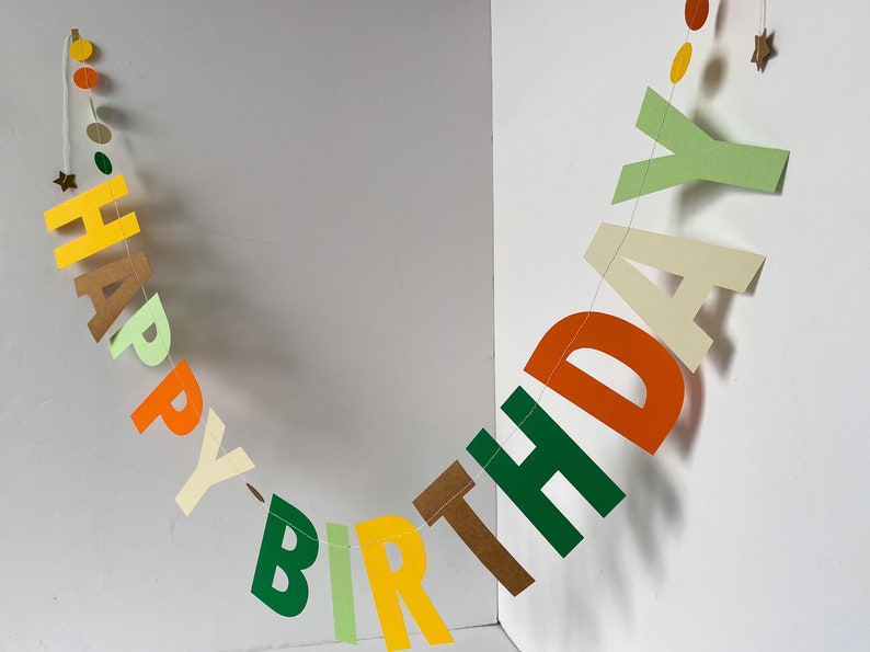 May include: A colorful paper banner with the words "Happy Birthday" in green, yellow, orange, and brown letters.