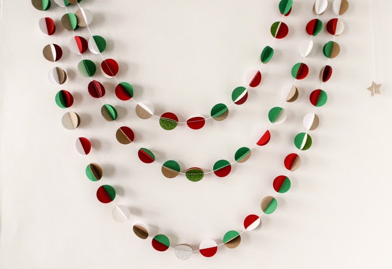 May include: A festive garland made of paper circles in red, green, and brown. The circles are strung together with white thread and are arranged in a repeating pattern.