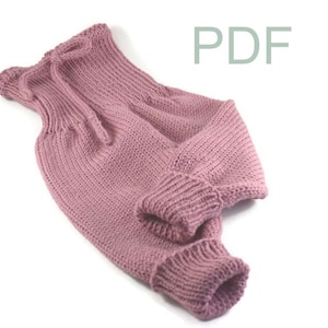 Könnte beinhalten: Ein rosa gestrickter Baby-Strampler mit einem Kordelzug am Hals. Der Strampler ist aus weichem, dickem Garn gefertigt und hat ein schlichtes, klassisches Design.