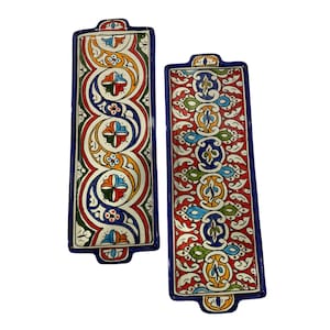 Puede incluir: Dos bandejas rectangulares de cerámica para servir con bordes azules y intrincados patrones coloridos. Los patrones presentan espirales, flores y diseños geométricos en tonos rojos, azules, verdes, amarillos y naranjas.