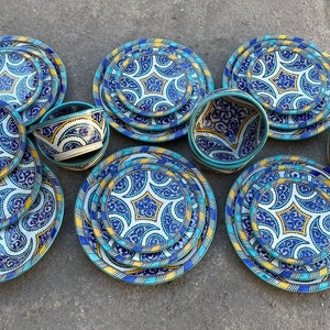 Puede incluir: Un juego de platos y cuencos de cerámica azul y blanca con intrincados patrones geométricos. Los platos están apilados en grupos de tres, y los cuencos están apilados en grupos de dos. Los platos y los cuencos están todos decorados con un patrón geométrico azul y blanco.