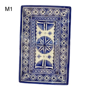 May include: A rectangular ceramic serving tray with a blue and white geometric pattern. The tray features a central starburst design surrounded by a border of intricate geometric shapes.