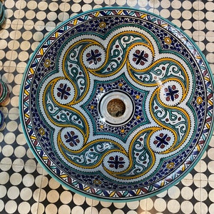 Puede incluir: Un lavabo grande y redondo de cer&aacute;mica con un intrincado patr&oacute;n floral en azul, verde, amarillo y blanco. El lavabo tiene un agujero de drenaje en el centro.