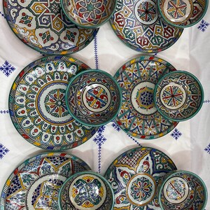 May include: Set of six ceramic plates and bowls with intricate geometric patterns in shades of blue, green, yellow, and red. The plates and bowls are decorated with a variety of floral and geometric designs.