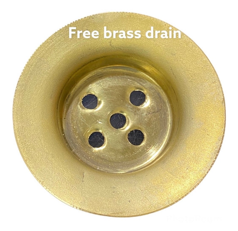 Puede incluir: Un desag&uuml;e de lat&oacute;n dorado con cinco agujeros. El texto "Free brass drain" est&aacute; escrito encima del desag&uuml;e.