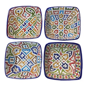Peut inclure: Ensemble de quatre bols carrés en céramique avec des motifs géométriques complexes dans des tons de bleu, vert, rouge, jaune et blanc. Les bols ont un bord bleu et sont parfaits pour servir des en-cas ou des trempettes.