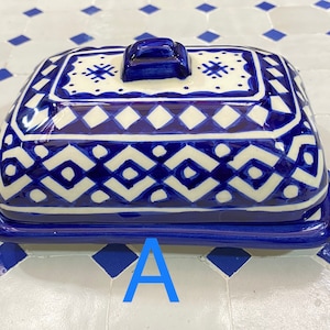 Op de afbeelding: Een blauwe en witte keramische botervloot met een geometrisch patroon. De vloot heeft een deksel met een knop bovenop.