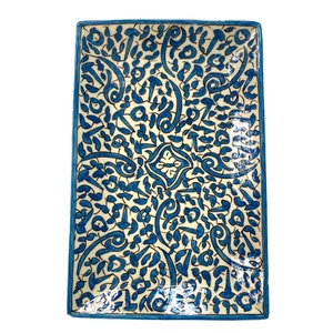 Puede incluir: Un plato rectangular de cerámica para servir con un intrincado patrón floral azul y blanco. El diseño presenta líneas en espiral y formas de paisley.