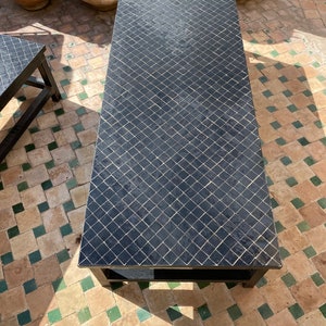 May include: Black coffee table with a tiled top. The tiles are arranged in a diamond pattern. The table has a black metal frame.