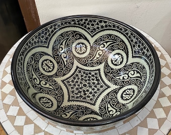 May include: A large, white ceramic bowl with a black and white geometric pattern. The bowl has a wide rim and a deep, round shape.