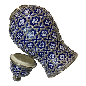 Puede incluir: Un jarr&oacute;n grande de cer&aacute;mica azul y blanco con ribete plateado y un intrincado patr&oacute;n floral. El jarr&oacute;n tiene una tapa con un dise&ntilde;o a juego.