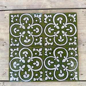 May include: Four green ceramic tiles with a white floral pattern. The tiles are arranged in a 2x2 grid.