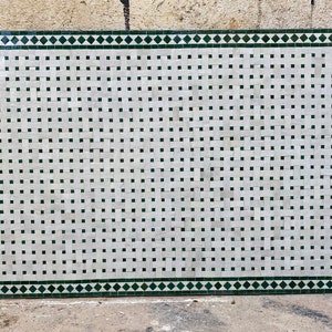 May include: A white and green mosaic tile floor with a geometric pattern. The tiles are arranged in a grid pattern with a green border.