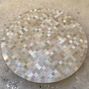 Può includere: Un piano da tavolo rotondo con un design a mosaico. Le piastrelle sono un mix di beige, marrone e bianco.
