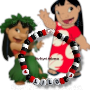 以下が含まれることがあります： 白い文字ビーズで「LILO」と綴られたビーズブレスレット。ブレスレットは、黒、赤、白のビーズと、ハート型のアクセントが特徴です。背景には漫画のキャラクターがいます。