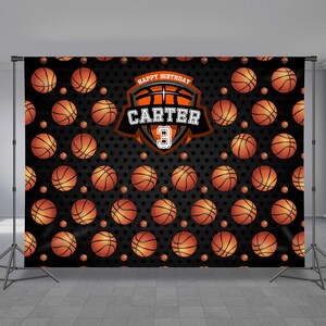 May include: A black and orange basketball themed backdrop with a basketball pattern and a shield with the text "Happy Birthday Carter 3".