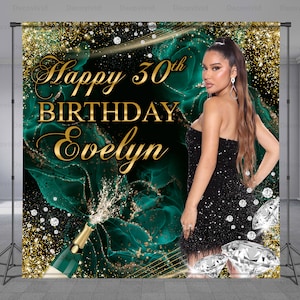 May include: A green and gold birthday backdrop with the text "Happy 30th Birthday Evelyn" and a woman in a black dress. The backdrop features a champagne bottle with a sparkling effect and a green and gold marble design.