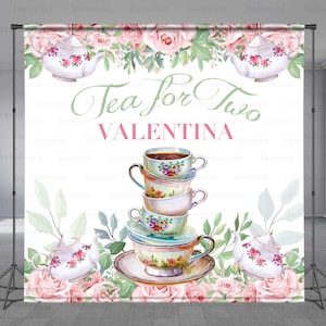 May include: A white backdrop with a pink and green floral border. The text "Tea for Two" is written in green script with the name "VALENTINA" written in pink below. A stack of four teacups and saucers is in the center of the backdrop. Two teapots with floral designs are on either side of the teacups.