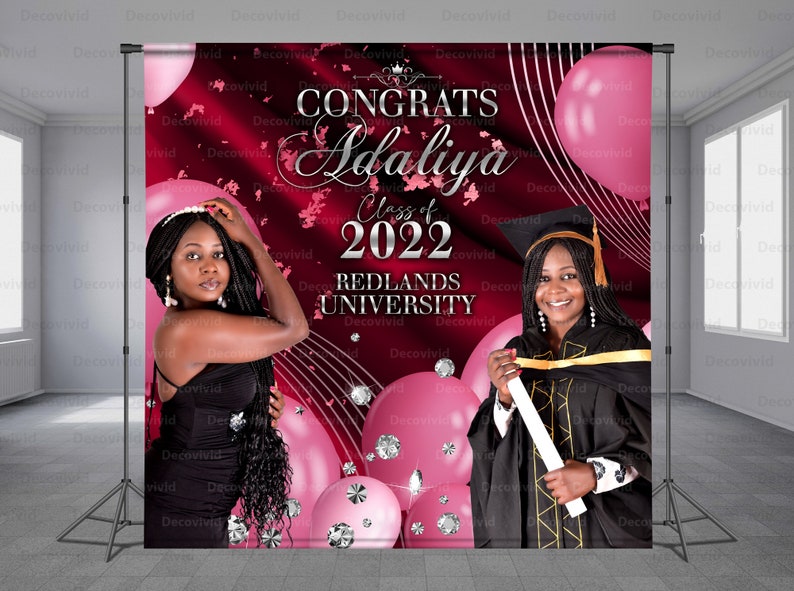 May include: A graduation backdrop with a red background and pink balloons. The text "CONGRATS Adaliya Class of 2022 REDLANDS UNIVERSITY" is printed in silver on the backdrop.