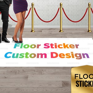 May include: A white floor sticker with the text "Floor Sticker Custom Design" in rainbow colors. The sticker is on a wooden floor with a gold floor sticker that says "Floor Sticker" in black text.