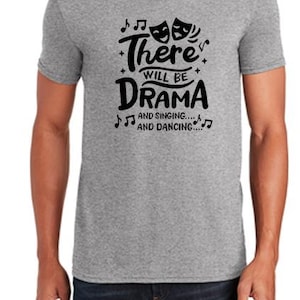 May include: A gray V-neck t-shirt with the text "There will be drama and singing... and dancing..." printed in black.