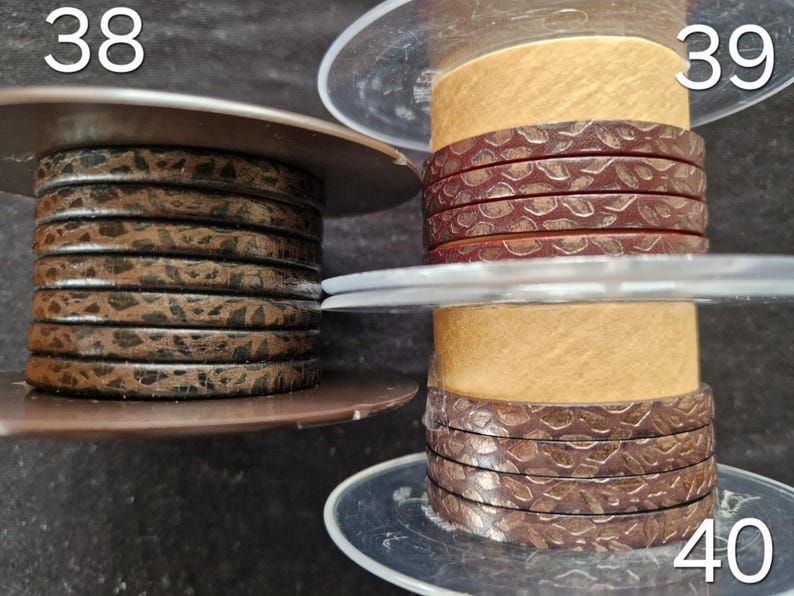 May include: Three plastic spools holding flat leather cord. Spool 38 features a dark brown cord with a black speckled pattern. Spool 39 displays a reddish-brown cord with a textured snake-skin pattern. Spool 40 shows a dark brown cord with a textured pattern.