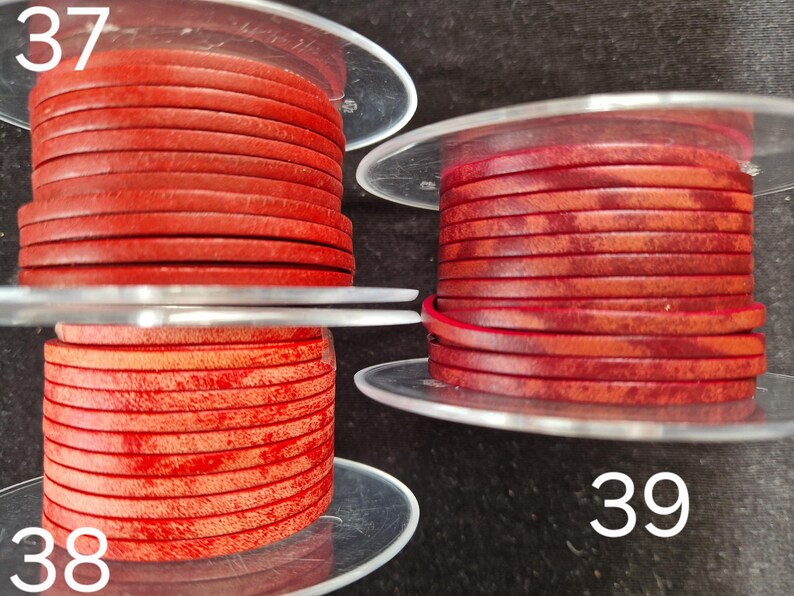 Pu&ograve; includere: Tre bobine di cordoncino in pelle rossa. Il cordoncino &egrave; avvolto in strati piatti e circolari. I numeri 37, 38 e 39 sono visibili sull'immagine. Il cordoncino appare di un colore rosso intenso e ricco.