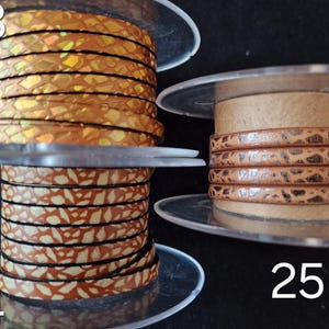 May include: Three spools of leather cord labeled 23, 24, and 25. Spool 23 features a metallic gold iridescent snakeskin pattern. Spool 24 displays a tan and white speckled design. Spool 25 shows a light brown cord with a dark brown textured pattern.