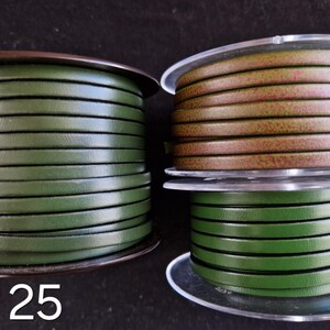 May include: Three spools of leather cord in shades of green and brown. The spools are labelled with the numbers 25, 26, and 27. The cord appears to be flat and is wound neatly around the spools, ready for crafting projects.