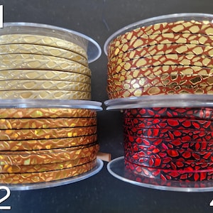 May include: Four spools of flat leather cord labeled 41, 42, 43, and 44. Spool 41 is metallic gold, 42 is iridescent bronze, 43 is metallic gold with a red crackle pattern, and 44 is black with a vibrant red crackle texture finish.