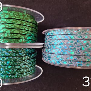 May include: Three spools of flat cord labeled 29, 30, and 31. Spool 29 features a vibrant green cord with a metallic, iridescent mosaic pattern. Spool 30 shows a similar green cord. Spool 31 displays a light gray cord with a blue iridescent mosaic finish.