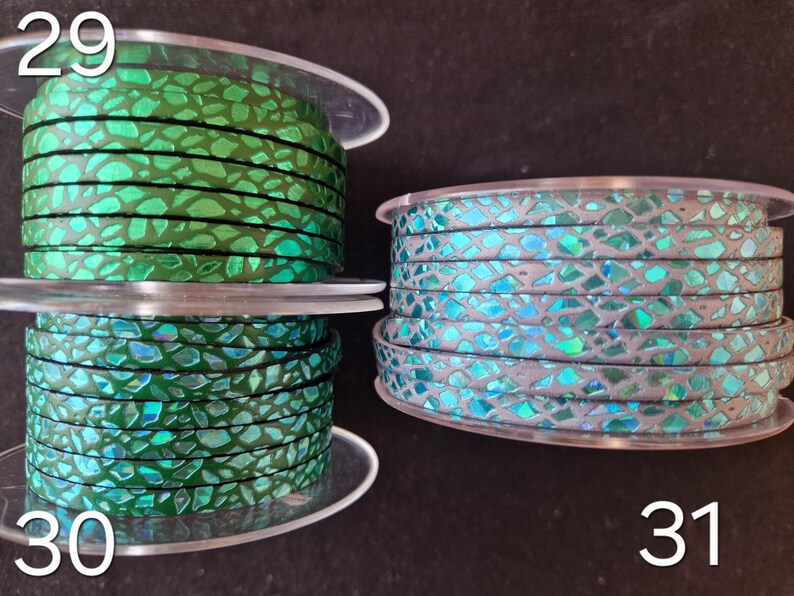 May include: Three spools of flat cord labeled 29, 30, and 31. Spool 29 features a vibrant green cord with a metallic, iridescent mosaic pattern. Spool 30 shows a similar green cord. Spool 31 displays a light gray cord with a blue iridescent mosaic finish.