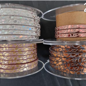 May include: Four spools of flat cord labeled 20, 21, and 22. Spool 20 features white cord with iridescent scales. Spool 21 shows pink cord with gold metallic leaf patterns. Spool 22 displays copper-colored cord with dark metallic scale textures.