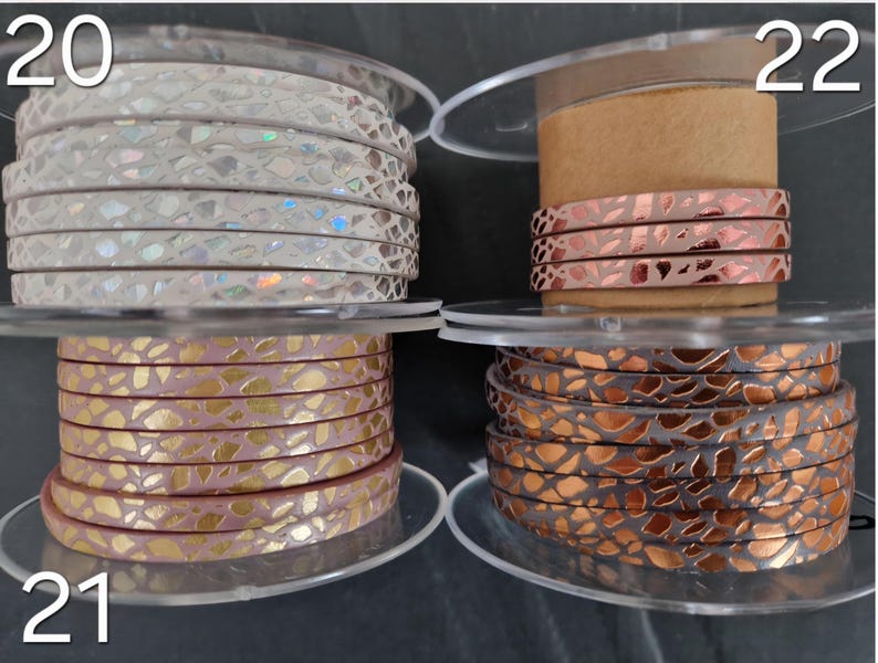 May include: Four spools of flat cord labeled 20, 21, and 22. Spool 20 features white cord with iridescent scales. Spool 21 shows pink cord with gold metallic leaf patterns. Spool 22 displays copper-colored cord with dark metallic scale textures.