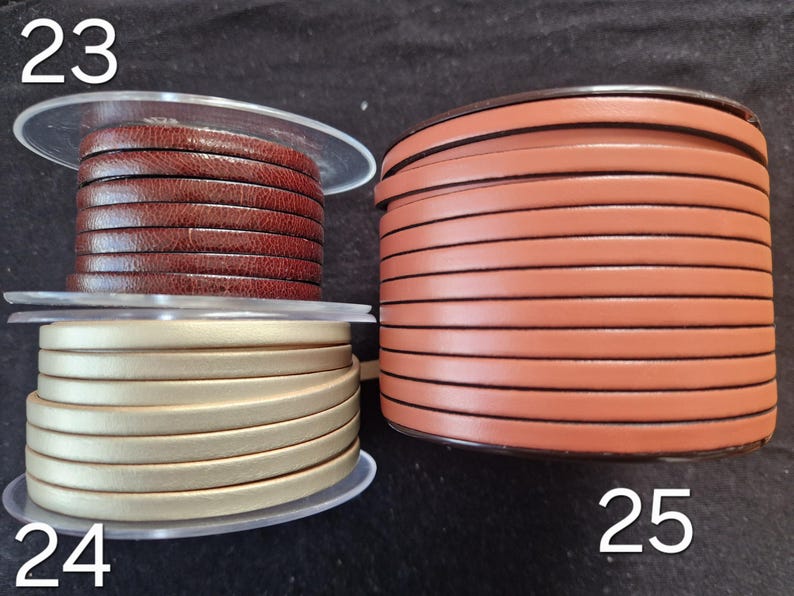 Pu&ograve; includere: Tre bobine di cordino in pelle piatta. La bobina 23 presenta una pelle testurizzata marrone scuro. La bobina 24 &egrave; un cordino in pelle color oro metallizzato. La bobina 25 &egrave; una bobina pi&ugrave; grande di pelle liscia color marrone chiaro.
