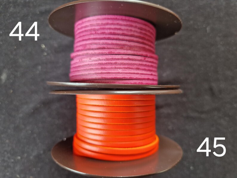 Pu&ograve; includere: Due bobine di cordoncino in pelle. La bobina superiore &egrave; di colore magenta intenso e la bobina inferiore &egrave; arancione brillante. Le bobine sono su uno sfondo scuro. I numeri 44 e 45 sono visibili sui lati sinistro e destro.