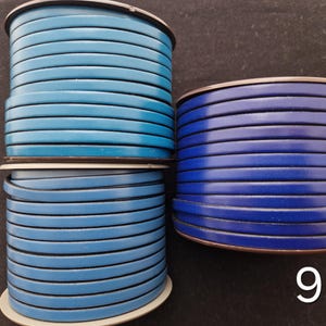 May include: Three spools of flat leather cord in shades of blue. The spools are stacked, with the top one in a lighter blue, the middle in a medium blue, and the bottom in a darker blue. The cords are neatly wound.