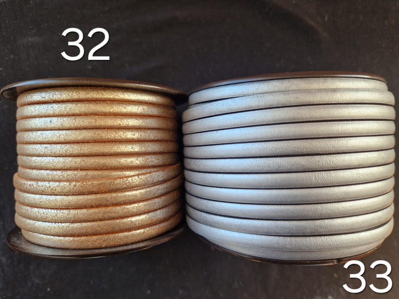 Pu&ograve; includere: Due bobine di cordino in pelle rotondo. La bobina a sinistra &egrave; contrassegnata dal numero 32 e presenta un cordino color rame metallizzato con finitura testurizzata. La bobina a destra &egrave; contrassegnata dal 33 e presenta un cordino in pelle argento opaco.