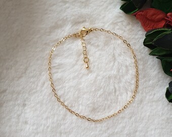 May include: A delicate gold chain anklet with a lobster clasp closure.