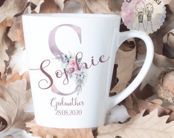 May include: White ceramic mug with a pink floral design and the name "Sophie" in cursive. The mug also has the text "Godmother 28.08.2020".